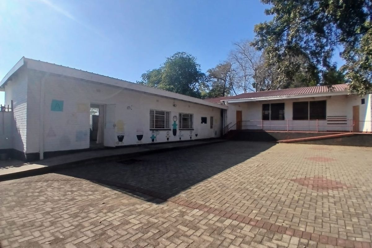 A view of the rear exterior courtyard featuring paved ground, brick building facades, and metal window frames.