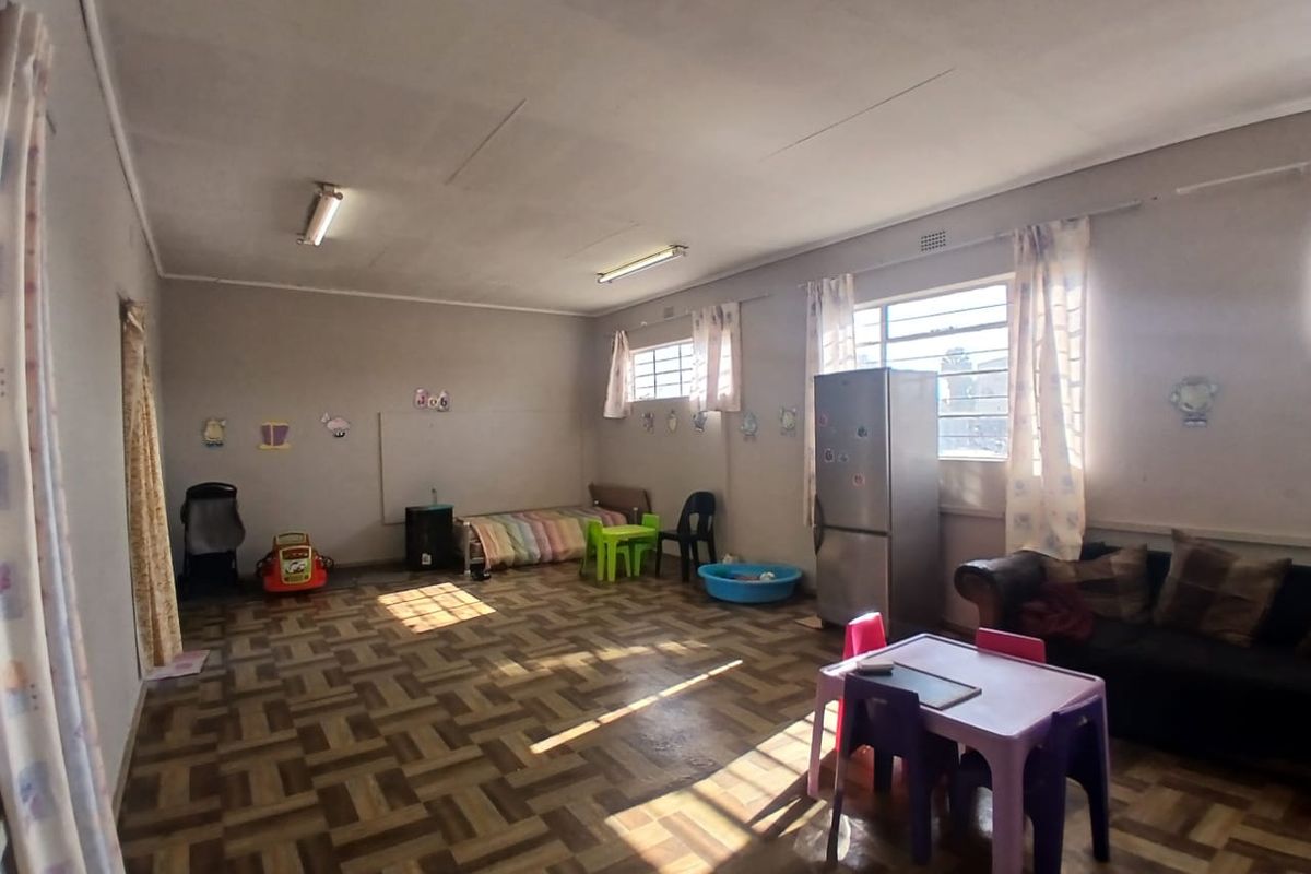 Spacious living area featuring traditional parquet flooring, steel frame windows, and fluorescent lighting, offering a versatile layout for commercial or residential use.