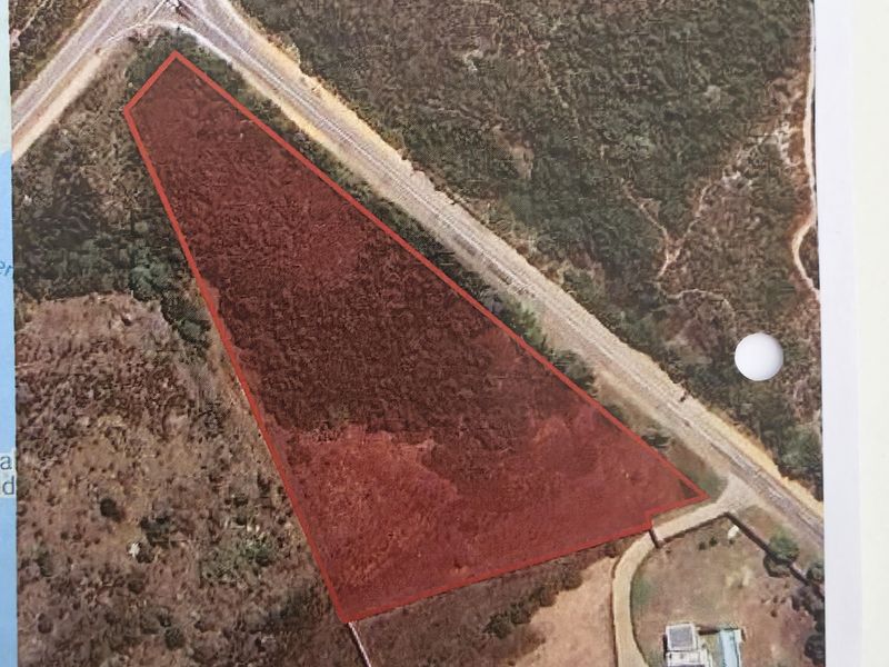 Aerial view of a rural farm property plot with defined boundaries, showing surrounding vegetation and access road infrastructure.