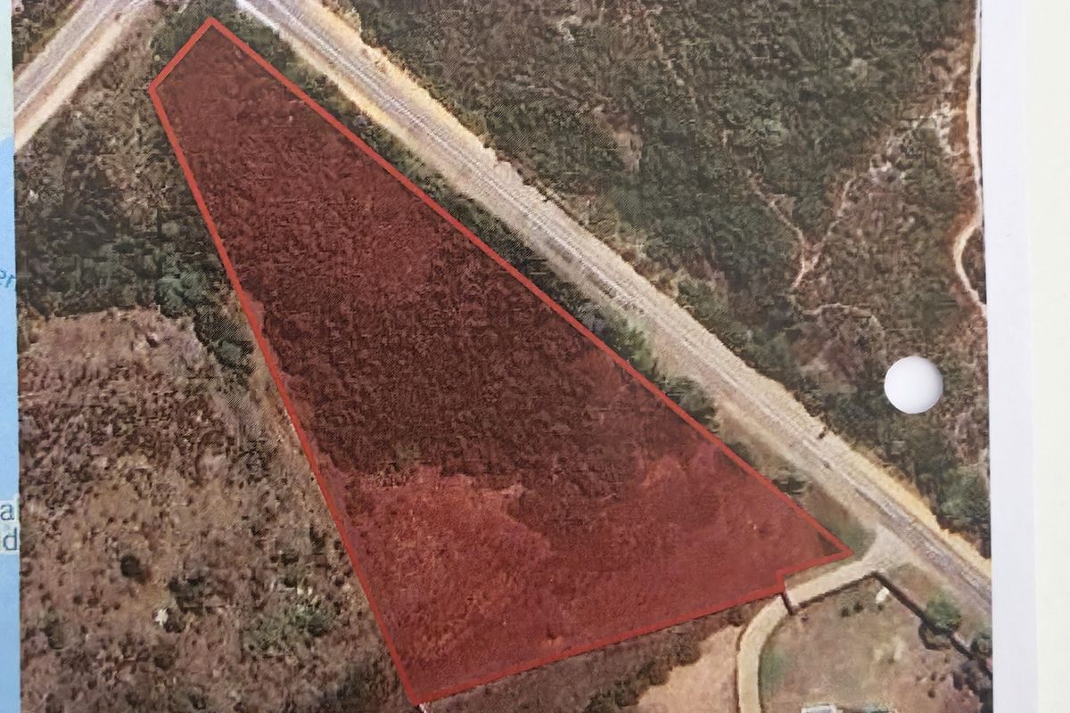 Aerial view of a rural farm property plot with defined boundaries, showing surrounding vegetation and access road infrastructure.