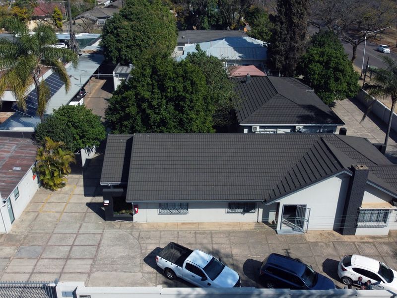 Aerial view of the office property featuring a tiled roof, extensive paved parking area, and secure perimeter fencing.
