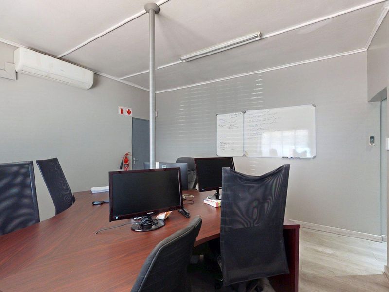 A functional office space featuring neutral wall finishes, a split-system air conditioner, and built-in storage cabinetry.