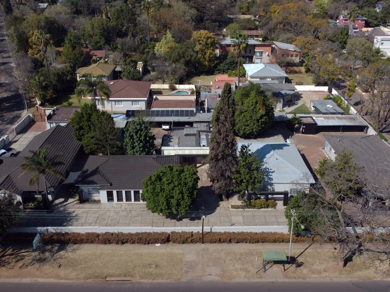 Aerial view of the office property showing multiple buildings, tiled roofs, solar installations, paved parking areas, and surrounding landscaped grounds.