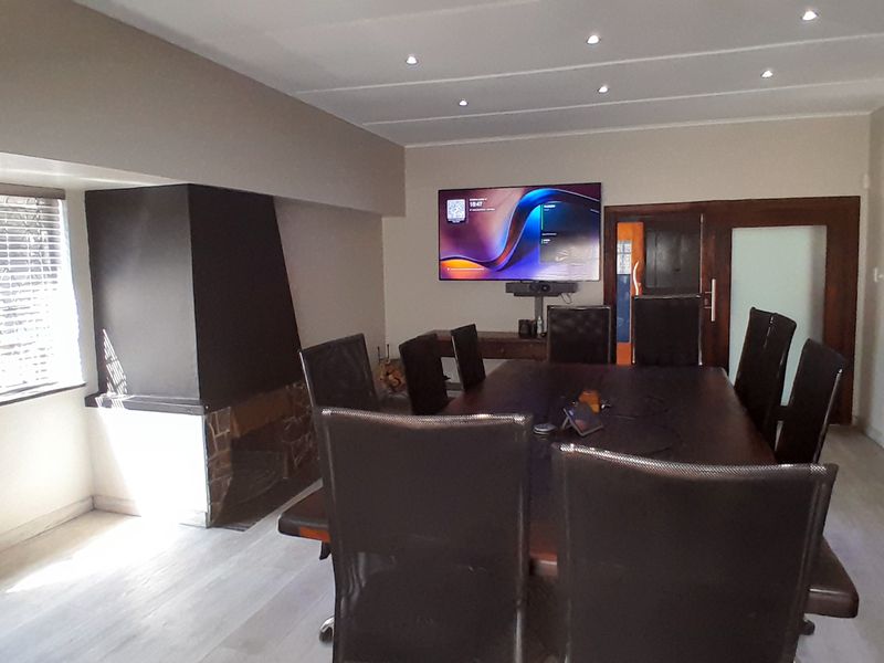 A professional office space featuring a large boardroom table, built-in fireplace, recessed ceiling lighting, and a modern glass-paneled door.