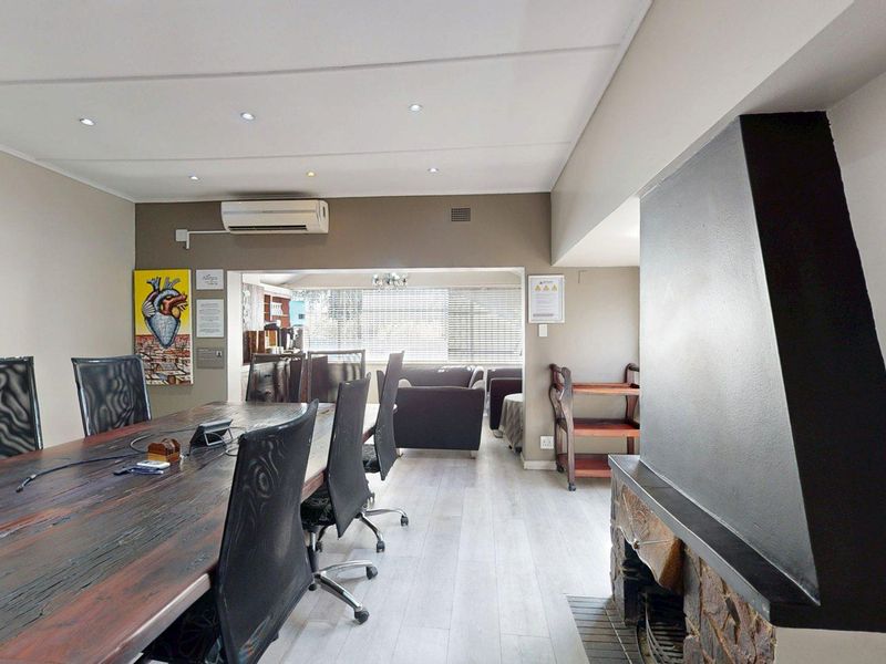 Spacious office area featuring a stone-clad fireplace, modern laminate flooring, recessed lighting, and a wall-mounted air conditioning unit.