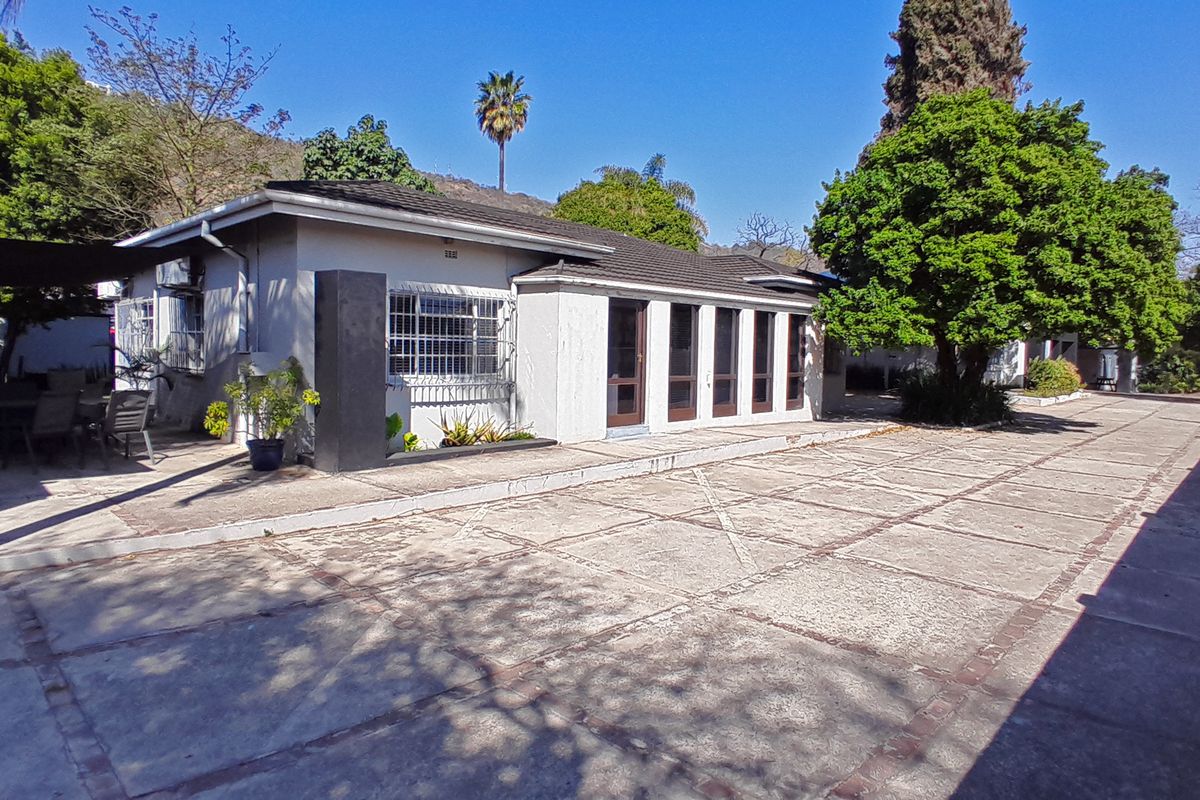 Rear exterior view of the office property featuring a large paved driveway, covered patio area, and secure window installations.