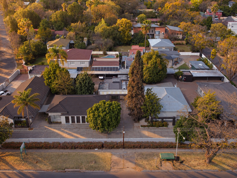 Aerial view of the office property showing multiple buildings, paved parking areas, solar panel installations, and surrounding landscaped grounds.