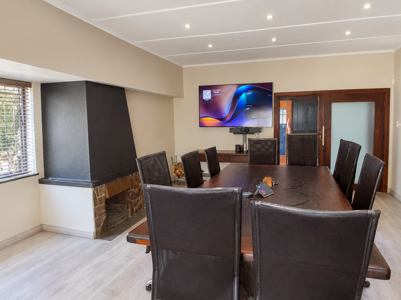 A professional office space featuring a built-in fireplace, recessed lighting, and modern laminate flooring, suitable for a boardroom or meeting area.