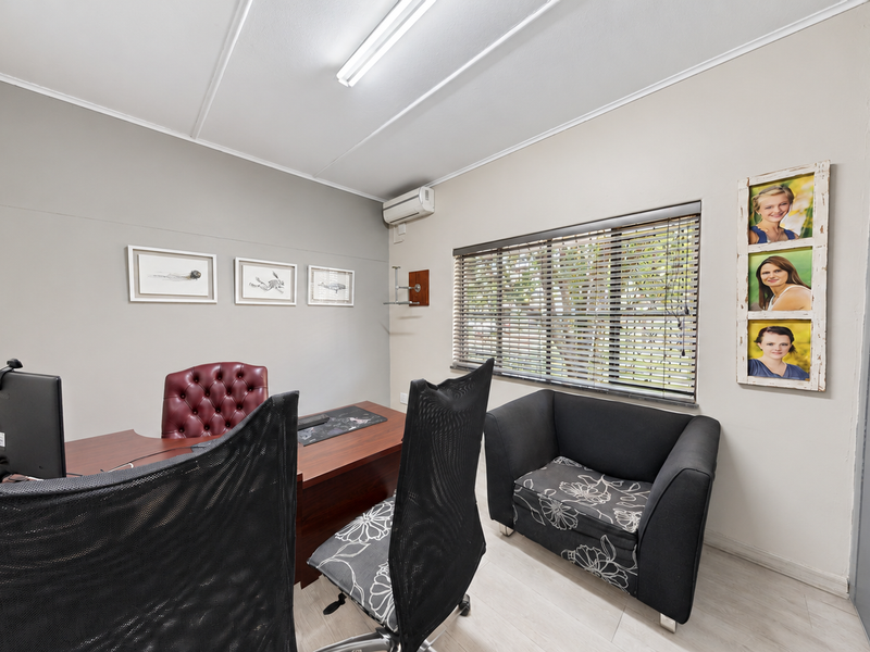 A functional office space featuring a split-system air conditioner, venetian blinds, and a built-in cupboard, providing a practical work environment.