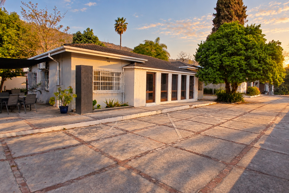 Rear exterior view of the office property featuring a large paved patio area, mature trees, and secure window fixtures under a tiled roof.