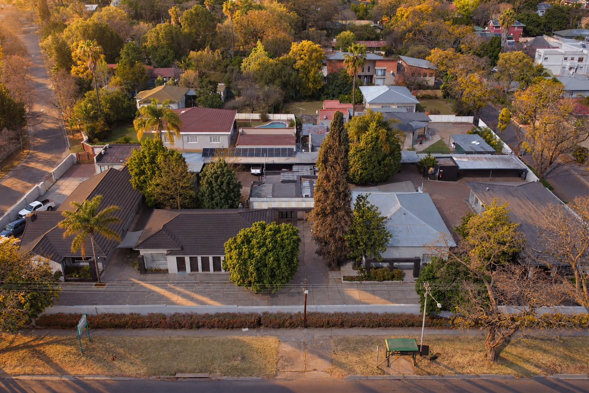 Aerial view of the office property showing multiple buildings, paved parking areas, solar panel installations, and surrounding landscaped grounds.