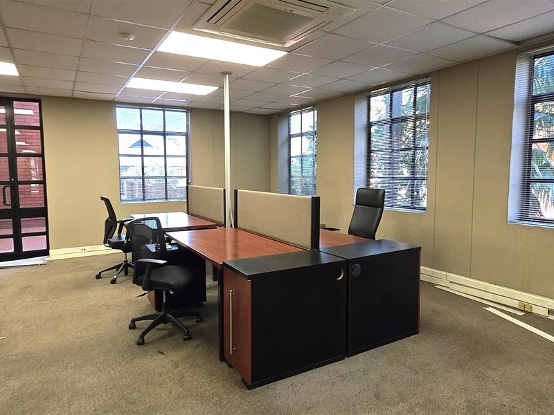Open plan office space featuring suspended ceilings, recessed lighting, ducted air conditioning, and large windows providing natural light.
