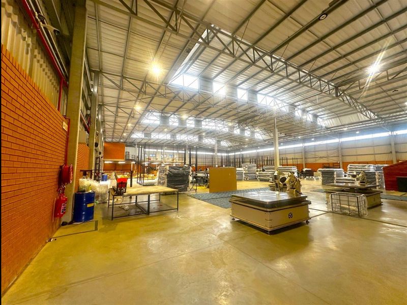 Spacious industrial warehouse featuring high-clearance steel roof trusses, polished concrete flooring, and ample natural light through integrated skylights.