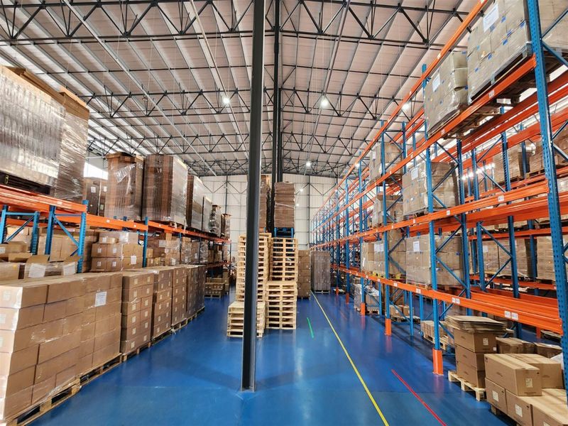 Spacious industrial warehouse featuring high-clearance ceilings, exposed steel trusses, durable epoxy-coated flooring, and extensive integrated steel pallet racking systems.