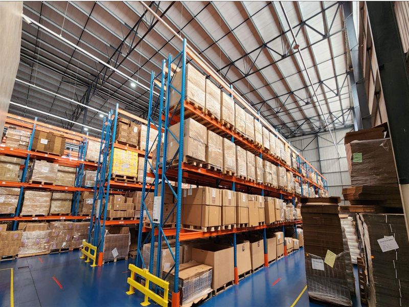Spacious industrial warehouse featuring high-clearance ceilings, exposed steel trusses, durable epoxy-coated flooring, and extensive heavy-duty pallet racking systems.