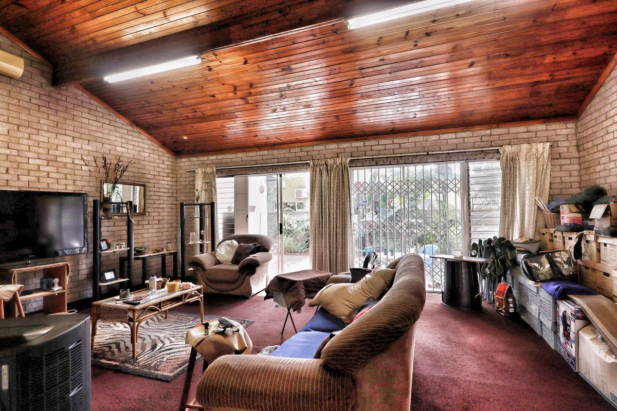Spacious living area featuring exposed brick walls, a high timber-paneled raked ceiling, and sliding glass doors providing access to the exterior.