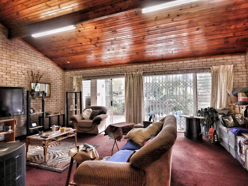 Spacious living area featuring exposed brick walls, a high timber-paneled raked ceiling, and sliding glass doors providing access to the exterior.