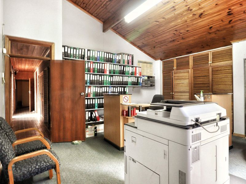 Functional office space featuring a vaulted timber-clad ceiling, built-in storage cabinetry, and integrated shelving units.