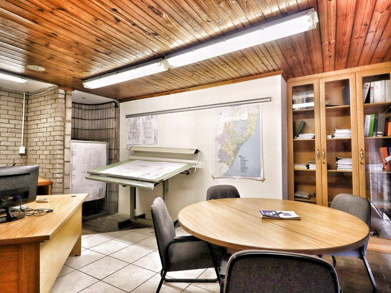 Functional office space featuring a timber-clad ceiling, exposed brick accents, tiled flooring, and built-in storage cabinetry.