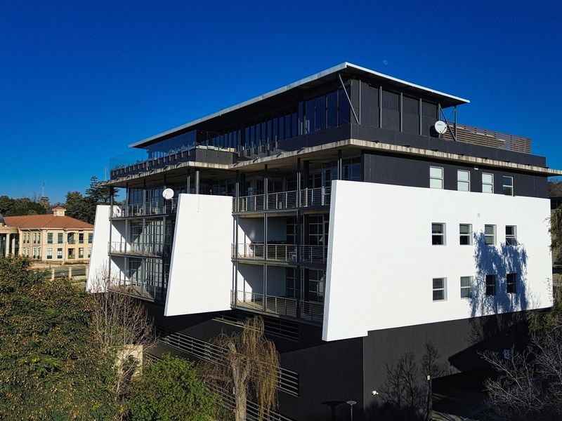 Aerial view of a modern multi-story office building featuring a contemporary facade, private balconies, and integrated parking facilities.