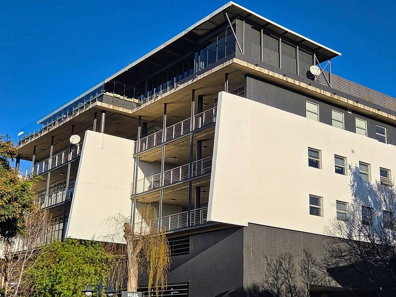 A modern multi-story office building featuring a contemporary facade with prominent white architectural panels, multiple balconies, and large windows.