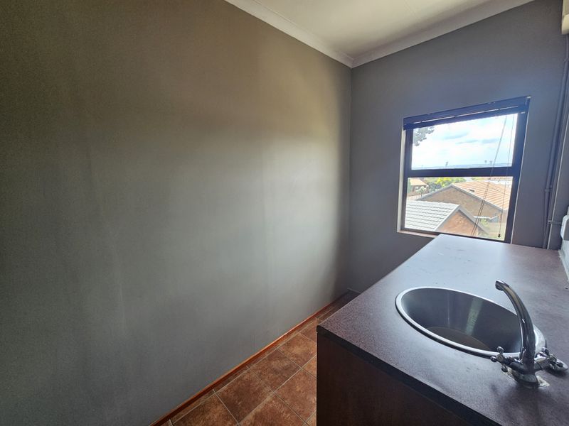 A functional scullery or utility area featuring a built-in sink, countertop, and tiled flooring, offering a practical space for preparation or cleaning tasks.