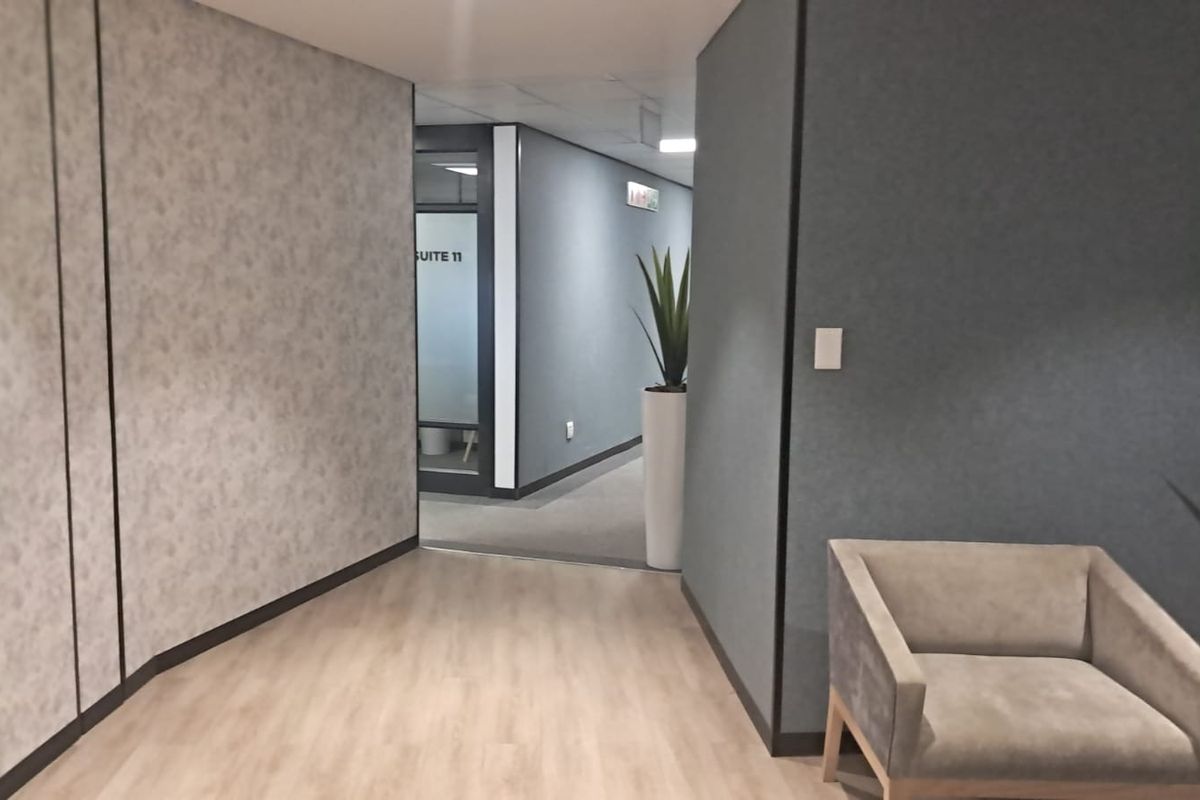 A modern office hallway featuring laminate flooring, textured wall finishes, and a glass-partitioned entrance to Suite 11.