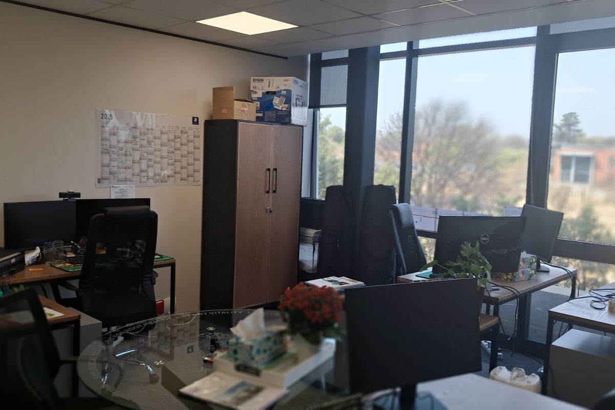 A functional office space featuring large floor-to-ceiling windows that provide ample natural light and views of the surrounding area.