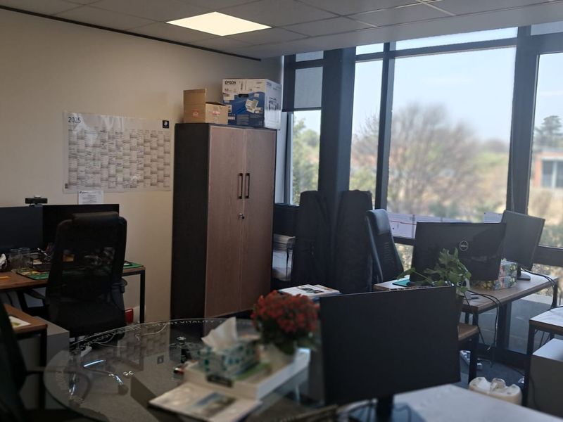 A functional office space featuring large floor-to-ceiling windows that provide ample natural light and views of the surrounding area.