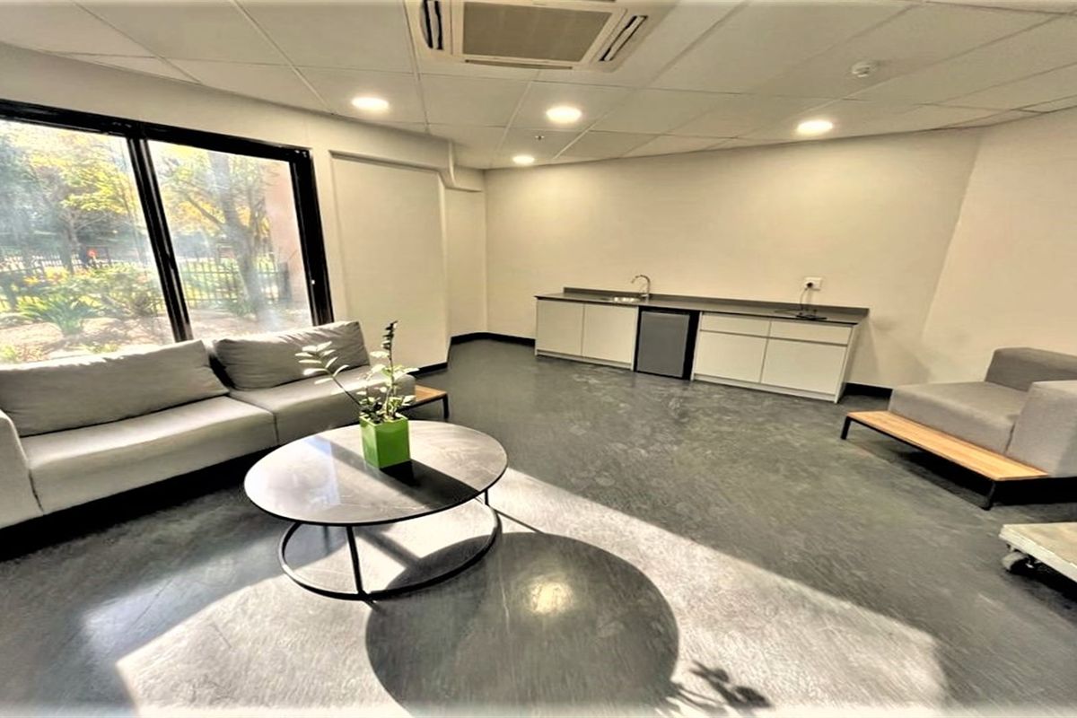 Modern office space featuring a built-in kitchenette, recessed lighting, suspended ceiling, and large sliding glass doors providing ample natural light.