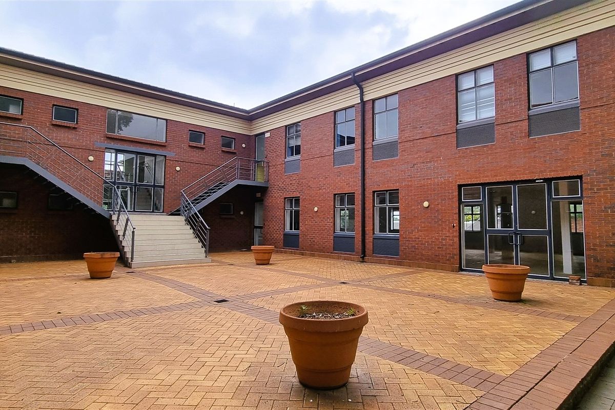 A paved courtyard area between office building wings, featuring external staircases and brick facade construction.