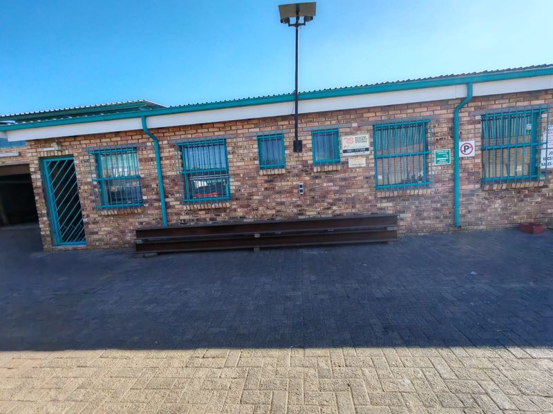 Industrial building exterior featuring face brick facade, secure steel window bars, and paved frontage with external lighting.