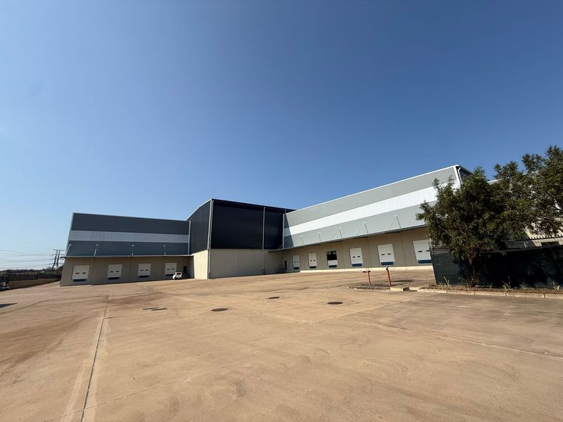 Spacious industrial facility featuring multiple loading bays with roller shutter doors and a large concrete yard area for logistics and vehicle access.