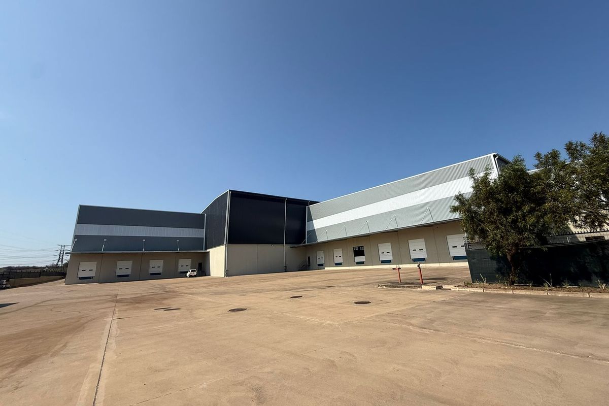 Large industrial warehouse facility featuring multiple loading bays, expansive concrete yard area, and modern metal cladding exterior.
