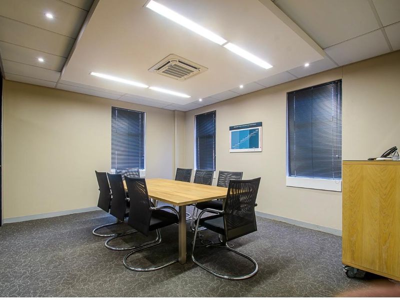 A professional office meeting room featuring a dropped ceiling with integrated lighting, cassette air conditioning, and carpeted flooring.