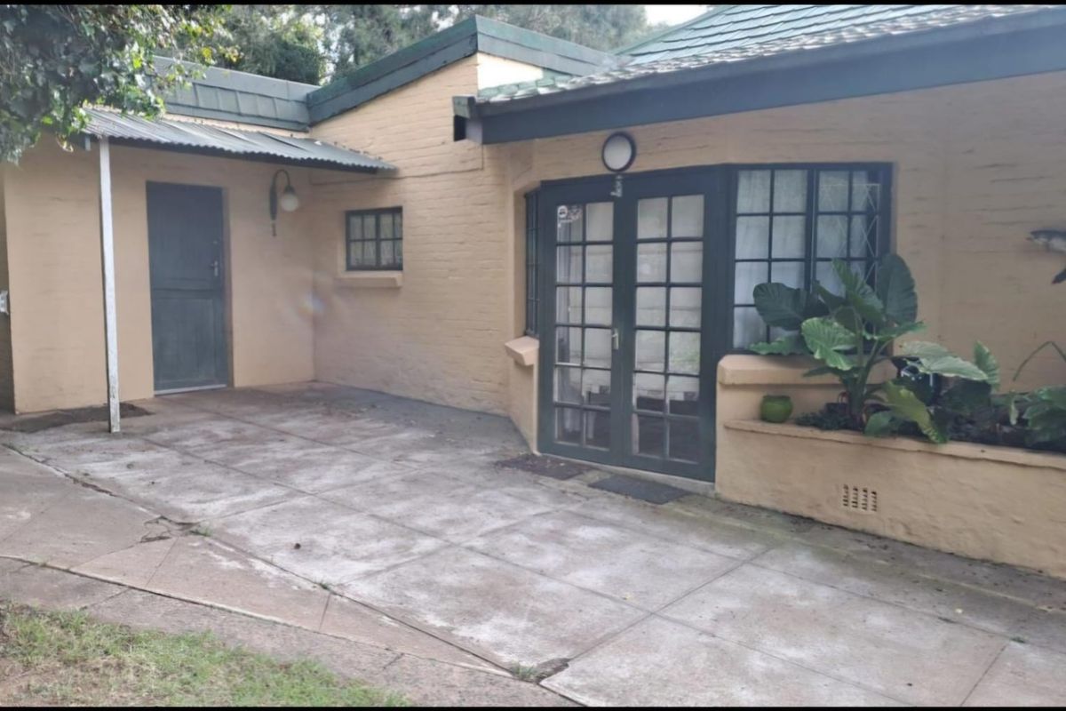 A paved outdoor patio area featuring French doors, a built-in planter box, and exterior lighting, providing a functional space for outdoor relaxation.