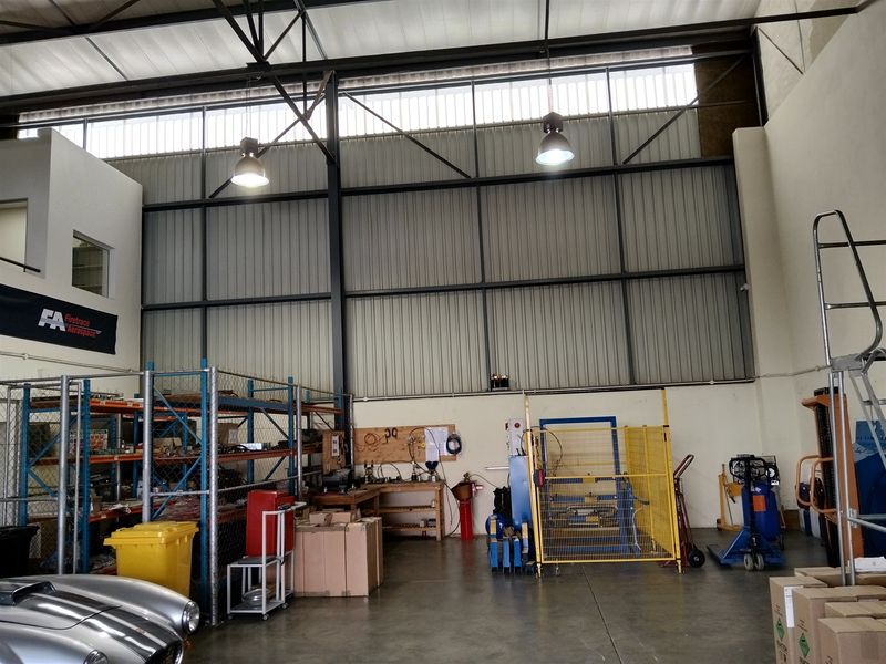 Spacious industrial utility area featuring high-bay lighting, exposed steel structural framing, and durable concrete flooring, suitable for workshop or storage operations.