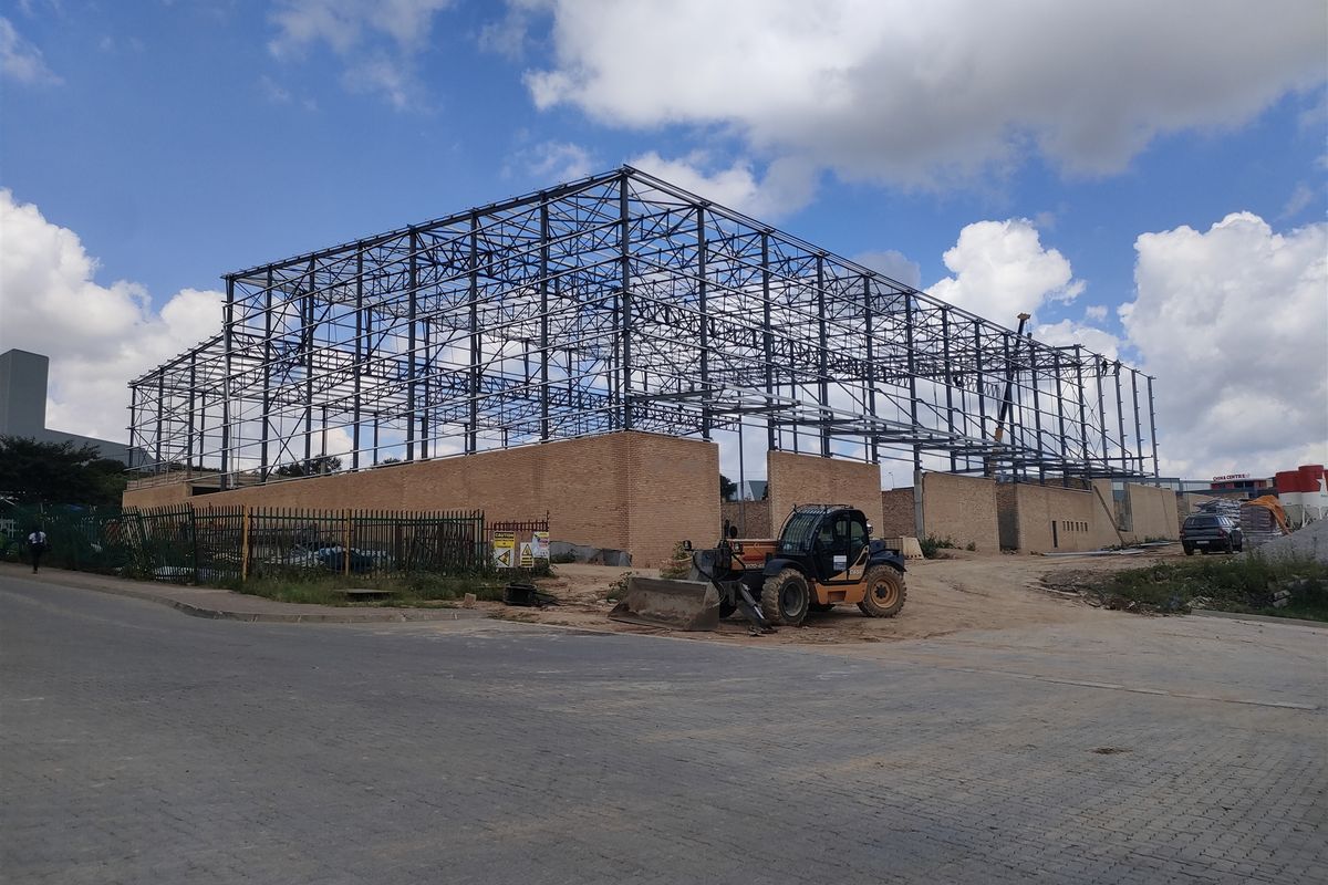 Industrial property under construction featuring a steel portal frame structure and brick masonry walls on a development site.