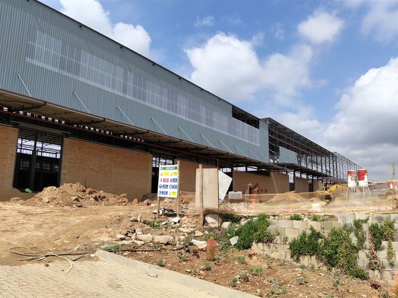 An industrial property currently under construction, featuring a large steel-framed structure with corrugated metal cladding and brick masonry walls.