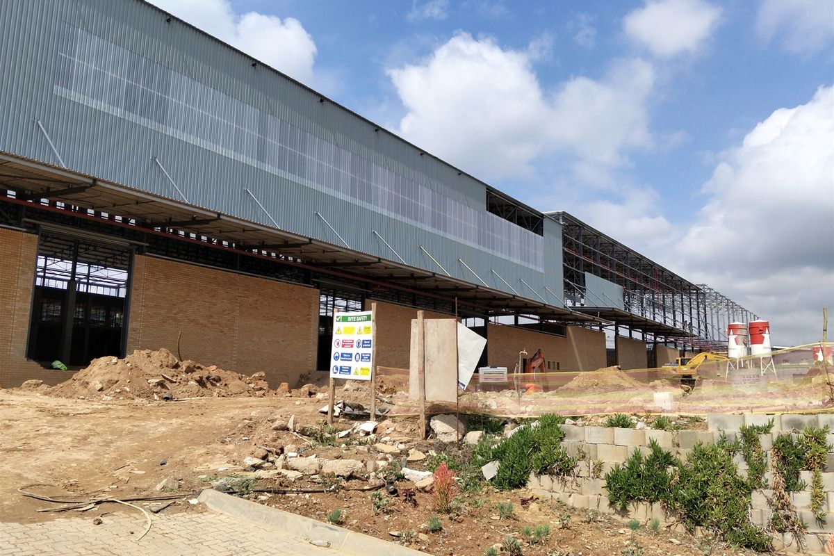 An industrial property currently under construction, featuring a large steel-framed structure with corrugated metal cladding and brick masonry walls.