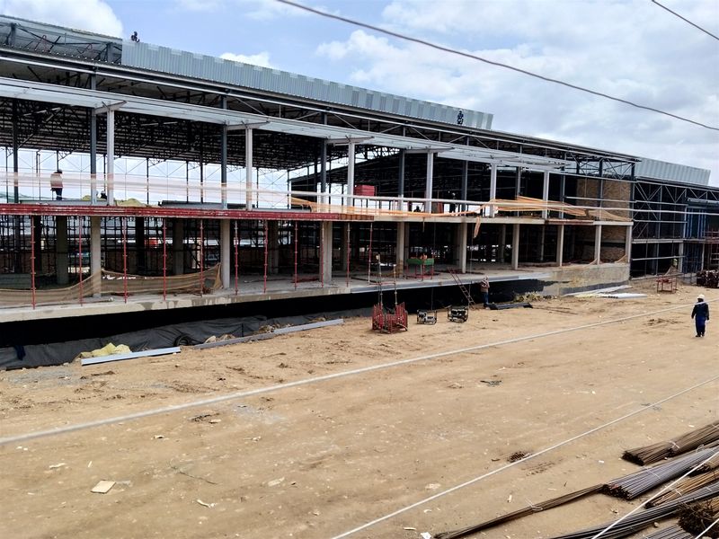 An industrial property under construction showing the steel frame structure, concrete columns, and metal roofing in progress.