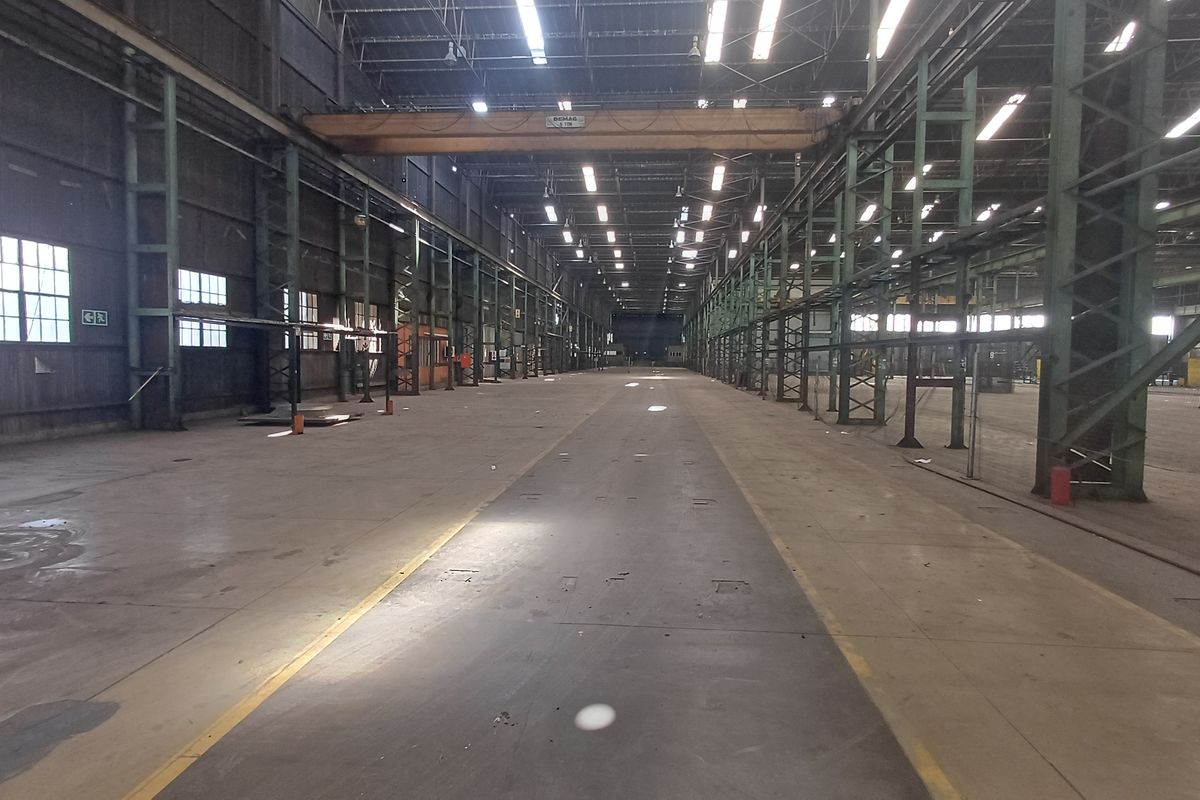 Expansive industrial warehouse space featuring high ceilings, steel structural framing, overhead gantry crane, and durable concrete flooring suitable for heavy-duty operations.