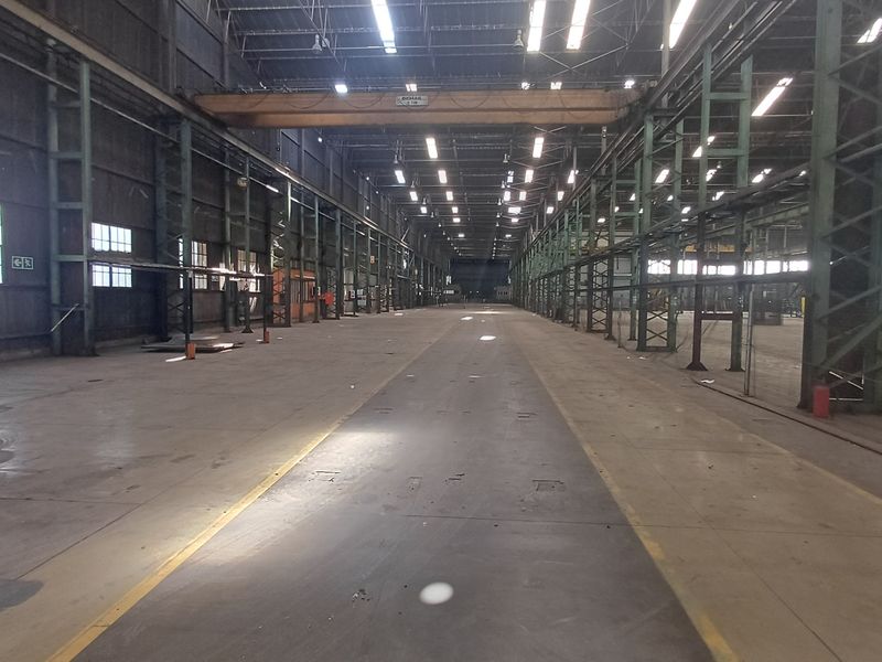 Expansive industrial warehouse space featuring high ceilings, steel structural framing, overhead gantry crane, and durable concrete flooring suitable for heavy-duty operations.