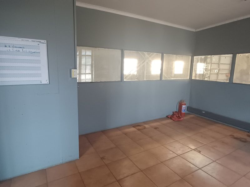 An empty office space featuring tiled flooring, internal glass partitions, and neutral wall finishes, suitable for a professional workspace or administrative area.
