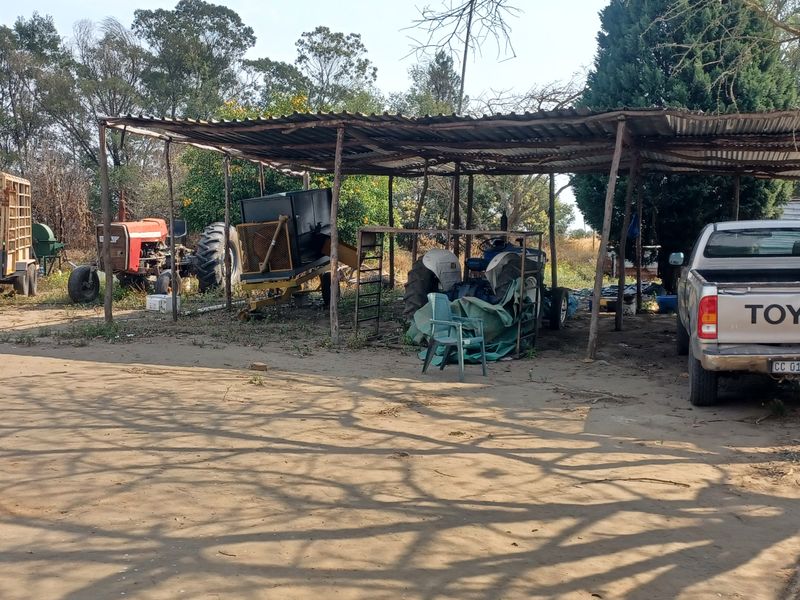 An open-sided farm utility shelter with a corrugated iron roof and timber support posts, used for equipment storage.