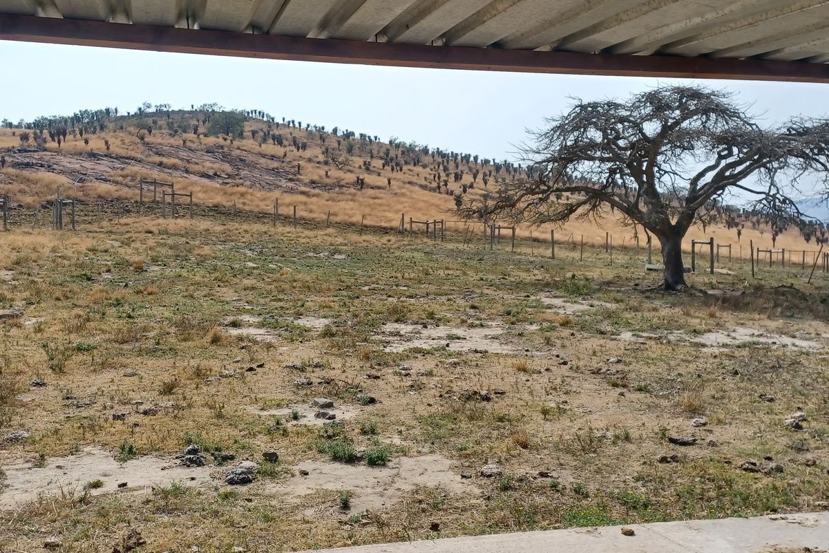 A covered outdoor patio area overlooking a rural landscape with wire fencing and natural terrain.
