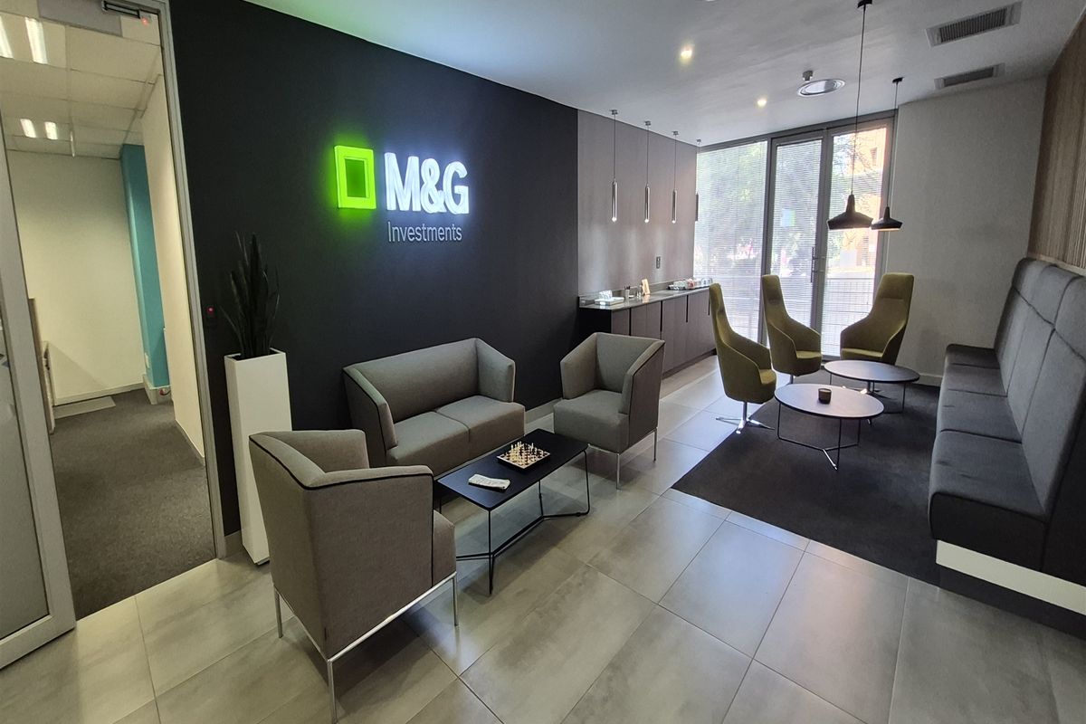 Modern office reception and waiting area featuring tiled flooring, recessed ceiling lighting, and a branded feature wall.