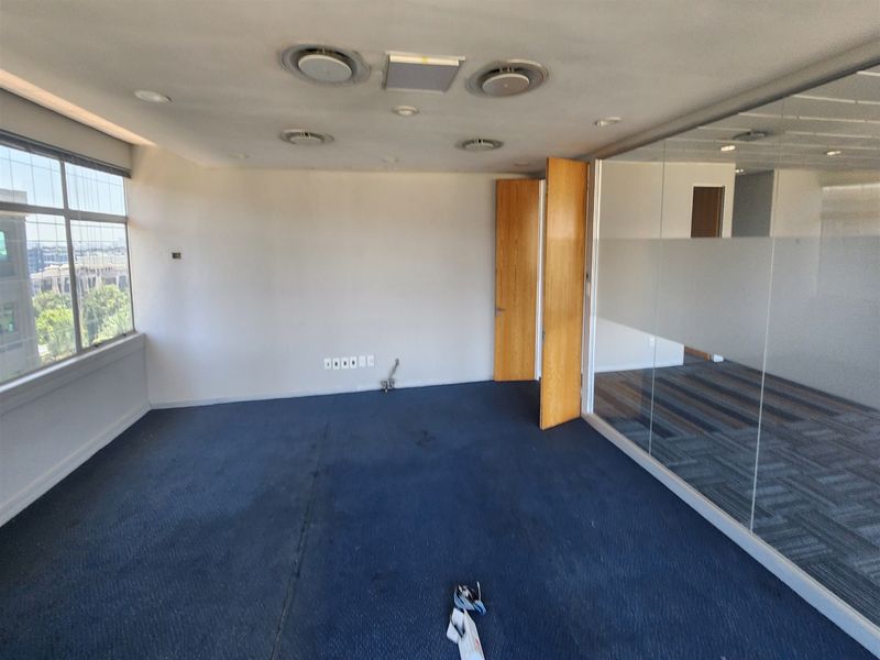 Empty office space featuring carpet flooring, ducted air conditioning, and a glass partition wall, offering a versatile layout for professional use.