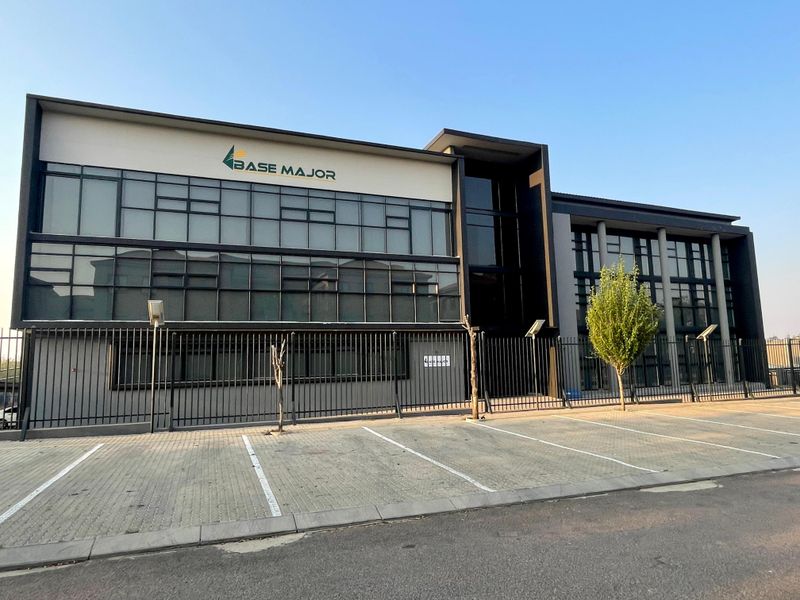 Modern multi-story commercial office building featuring extensive glass curtain walling, secure perimeter fencing, and dedicated paved parking facilities.