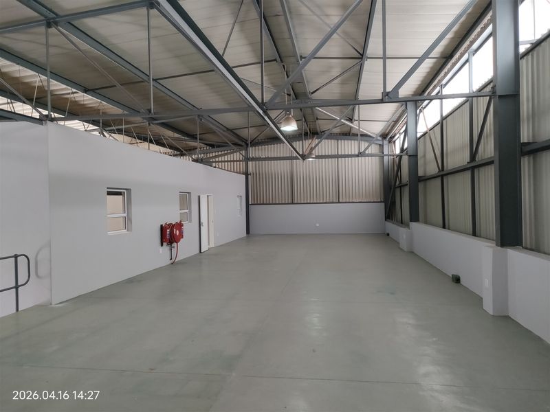 Spacious industrial warehouse unit featuring high-clearance steel truss roofing, polished concrete flooring, and integrated fire safety equipment.